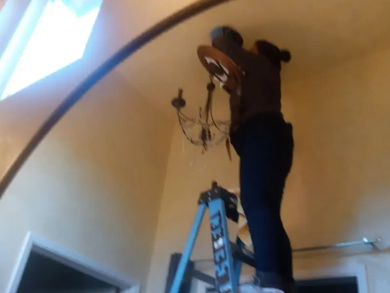 Electrician installing a chandelier in a Hitchcock residence